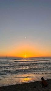 eine Person, die am Strand sitzt und den Sonnenuntergang beobachtet in der Unterkunft Au cœur des Roches in Saint-Paul
