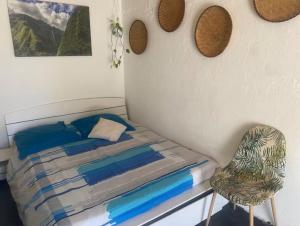 ein kleines Schlafzimmer mit einem Bett und einem Stuhl in der Unterkunft Au cœur des Roches in Saint-Paul