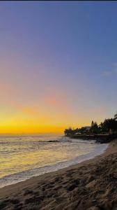 einen Strand mit Sonnenuntergang im Meer in der Unterkunft Au cœur des Roches in Saint-Paul