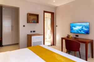a bedroom with a bed and a desk and a television at The Meru House in Nkubu