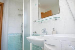 een witte badkamer met een wastafel en een spiegel bij Sunset Apartments Bohinj in Bohinj +16 foto's