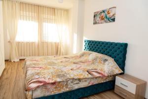 a bedroom with a bed with a blue headboard at Apartmani Loznica Premia in Loznica