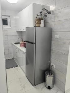een roestvrijstalen koelkast in een keuken met witte kasten bij Apartmani B&R in Lazarevac +5 foto's