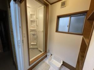 a small bathroom with a walk in shower next to a window at 伊東駅前ゲストハウス in Ito