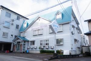 a white building with a sign in front of it at Guest house SENWA in Yuzawa