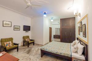 a bedroom with a bed and two chairs and a tv at Chomu Bagh Hotel & Resorts in Chomu in Jaipur