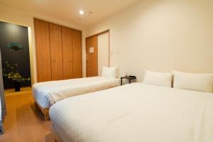 two beds in a hotel room with white sheets at Homey Inn SANNO in Kyoto