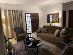 Una sala de estar con un sofá, una mesa y sillas. en Home in Airport Residential- 2 mins from airport, en Accra