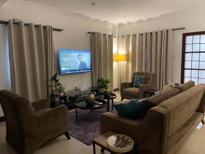Una sala de estar con un sofá y un televisor de pantalla plana. en Home in Airport Residential- 2 mins from airport, en Accra