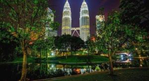 un parco con due alte torri di notte di The Hulo Hotel & Gallery a Kuala Lumpur