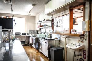 a large kitchen with a stove and a sink at Guest house SENWA in Yuzawa