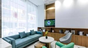 a living room with a blue couch and a table at Magnotel Hotel Dongxing Guomen Port in Tung-hsing-shih