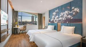 a hotel room with two beds and a painting on the wall at Magnotel Hotel Dongxing Guomen Port in Tung-hsing-shih +180 photos