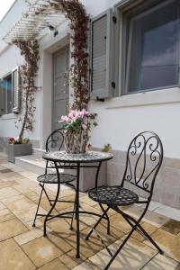 zwei Stühle und ein Tisch mit einer Vase mit Blumen in der Unterkunft Dimora Giardinelli in Fasano