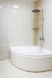 杜尚别Vatan Hotel的带淋浴的浴室里的白色浴缸