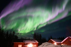 uma aurora no céu sobre uma casa em Hotel Glamping Gällivare - Laponia Sky Hut - Norrbotten - Lappland - Northern Lights em Koskullskulle
