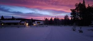 uma casa na neve à noite com um pôr do sol em Hotel Glamping Gällivare - Laponia Sky Hut - Norrbotten - Lappland - Northern Lights em Koskullskulle
