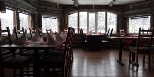 uma sala de jantar com mesas, cadeiras e janelas em Hotel Glamping Gällivare - Laponia Sky Hut - Norrbotten - Lappland - Northern Lights em Koskullskulle