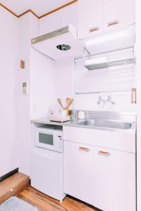 Una cocina con gabinetes blancos y un fregadero. en Fukuoka Hakata Stay 1BR with Balcony, TV and Laundry 206, en Wada