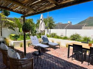 a patio with chairs and a table and an umbrella at Ibis Cottage Hout Bay with Mountain View Terrace in Hout Bay