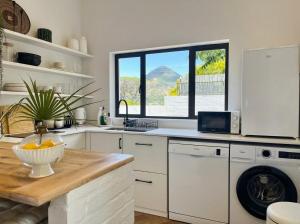 a kitchen with a sink and a dishwasher at Ibis Cottage Hout Bay with Mountain View Terrace in Hout Bay