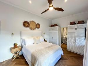 a bedroom with a white bed and a ceiling fan at Ibis Cottage Hout Bay with Mountain View Terrace in Hout Bay