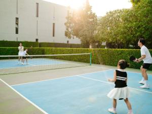 a group of people playing tennis on a tennis court at SO/ Sofitel Hua Hin in Cha Am