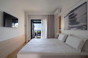 a bedroom with a large white bed with a painting on the wall at Coral Hotel Athens in Athens +86 photos