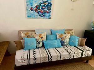 un canapé avec des oreillers et un tableau sur le mur dans l'établissement La Preneuse sur Mer Appartement, à Rivière Noire