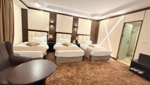 a hotel room with three beds and a mirror at Rojina Hotel in Amman