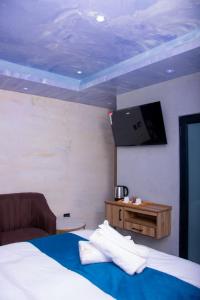 ein Schlafzimmer mit einem Bett und einem Fernseher an der Wand in der Unterkunft Meriam Base Lodge in Kempton Park