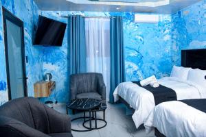 ein blaues Zimmer mit 2 Betten und einem Stuhl in der Unterkunft Meriam Base Lodge in Kempton Park