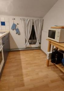 a kitchen with a wooden floor and a microwave at Kleine Strandperle in Fehmarn
