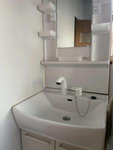 ein weißes Badezimmer mit Waschbecken und Spiegel in der Unterkunft YAMADERA Family House in Wada
