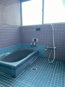 ein blau gefliestes Badezimmer mit Badewanne und Dusche in der Unterkunft YAMADERA Family House in Wada