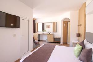 a hotel room with a bed and a desk at Семеен Хотел Флора in Zlatograd