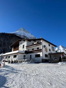 a large white building with a mountain in the background at Hotel Alpina in Galtür