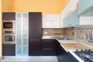 een keuken met zwarte kasten en witte apparaten bij Hostdomus - Il Maestrale Apartment in Alassio