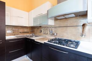 een keuken met witte kasten en een kookplaat oven bij Hostdomus - Il Maestrale Apartment in Alassio