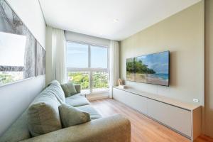 ein Wohnzimmer mit Couch und großem Fenster in der Unterkunft Rivieira 2 Suítes e Jacuzzi by Achei Camboriu in Cabeçudas