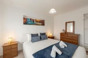 a bedroom with a large white bed with blue pillows at Ocean Breeze Baleal in Ferrel
