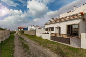 a dirt road next to a white building at Ocean Breeze Baleal in Ferrel