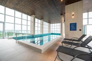 ein Swimmingpool in einem Gebäude mit Stühlen davor in der Unterkunft Rivieira 2 Suítes e Jacuzzi by Achei Camboriu in Cabeçudas