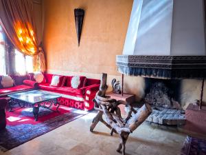 ein Wohnzimmer mit einem roten Sofa und einem Kamin in der Unterkunft Hotel Taddart in Midelt