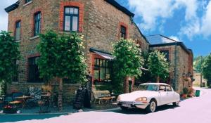 een witte auto geparkeerd voor een bakstenen gebouw bij L'Ancienne Boulangerie in Durbuy