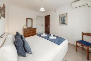 a bedroom with a white bed and a chair at Ocean Breeze Baleal in Ferrel