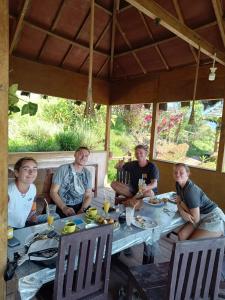 Watuburu Cottage & Restaurant في كيليموتو: مجموعة شباب جالسين حول طاولة