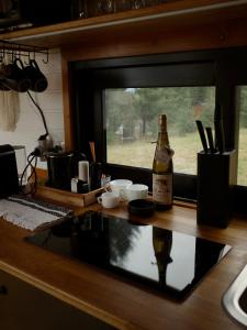 Una botella de champán sentada en un mostrador en una cocina en Natura Tiny House, en Mărişel 3 fotos más
