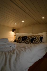 Una cama con sábanas blancas y almohadas en una habitación. en Natura Tiny House, en Mărişel