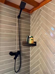 Una ducha con un cabezal de ducha negro en una pared. en Natura Tiny House, en Mărişel